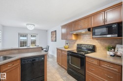 Wood-finish cabinetry, tile flooring, stone-finish countertops, stainless steel sink, and a tile backsplash - 