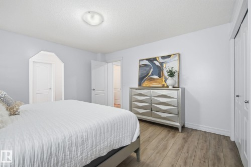 Wood-finish flooring, white paneled doors, and a ceiling-mounted light fixture - 3016 24 Ave Nw, Edmonton, AB - Indoor Photo Showing Bedroom
