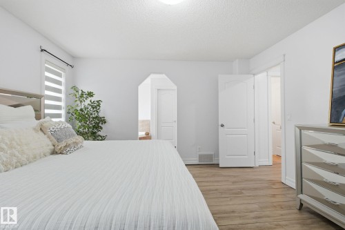 Recessed lighting, wood-finish flooring, white paneled doors, window with horizontal blinds, and an arched doorway - 3016 24 Ave Nw, Edmonton, AB - Indoor Photo Showing Bedroom