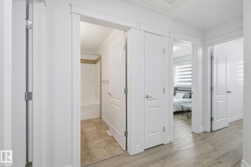 White paneled doors, light wood-finish flooring, and crown molding details - 3016 24 Ave Nw, Edmonton, AB - Indoor Photo Showing Other Room