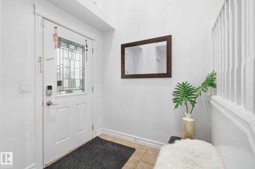 Entryway featuring a white door with a leaded glass insert, a digital keypad lock, and a framed mirror - 3016 24 Ave Nw, Edmonton, AB - Indoor Photo Showing Other Room