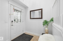 Entryway featuring a white door with a leaded glass insert, a digital keypad lock, and a framed mirror - 