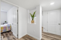 Wood-finish flooring throughout, bright white walls, recessed ceiling lighting, and white interior doors - 