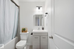 Vanity with integrated sink, chrome faucet, wall-mounted light fixture, and a toilet - 