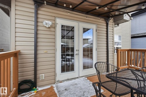 Outdoor deck with wood-finish railing, double glass-paned doors, and exterior wall siding - 3016 24 Ave Nw, Edmonton, AB - Outdoor With Exterior