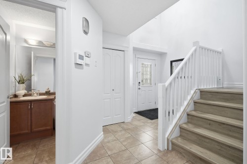 Tiled entryway with wood-finish stairs, white railing, and a front door with decorative glass - 3016 24 Ave Nw, Edmonton, AB - Indoor Photo Showing Other Room