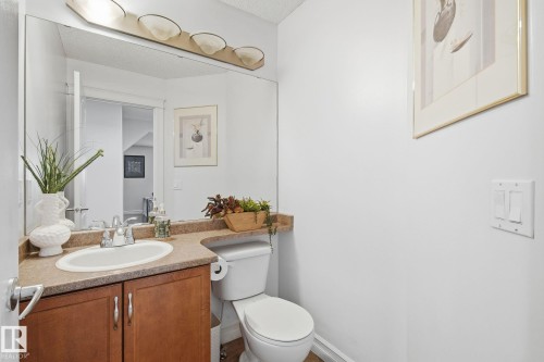Wood-finish vanity with a drop-in sink, dual-handle faucet, and light-toned countertop - 3016 24 Ave Nw, Edmonton, AB - Indoor Photo Showing Bathroom