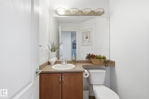 Integrated vanity with a single basin sink, wood-finish cabinetry, and a full-width mirror - 3016 24 Ave Nw, Edmonton, AB - Indoor Photo Showing Bathroom