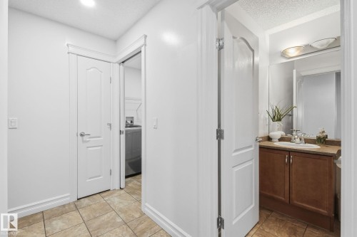 Tiled flooring throughout, white interior doors with contemporary hardware, and a vanity with a surface-mount sink and a wall-mounted light fixture - 3016 24 Ave Nw, Edmonton, AB - Indoor Photo Showing Other Room