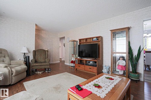 Living area featuring wood-finish flooring, textured wall finishes, and a neutral ceiling - 5203 45 Street, Beaumont, AB - Indoor Photo Showing Living Room