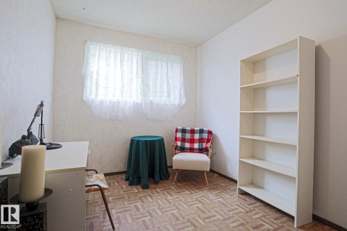 Room featuring a white built-in bookcase with five shelves, parquet wood-finish flooring, and two windows - 5203 45 Street, Beaumont, AB - Indoor