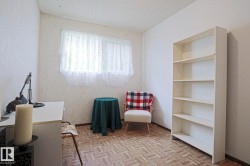 Room featuring a white built-in bookcase with five shelves, parquet wood-finish flooring, and two windows - 