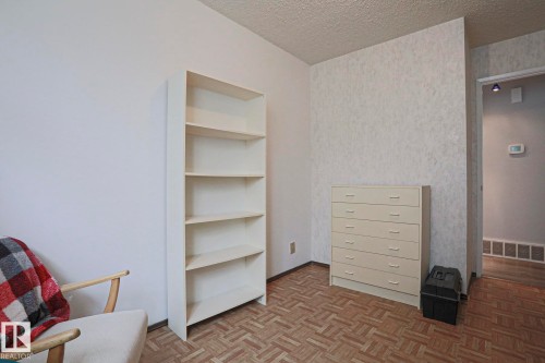 Parquet wood-finish flooring with patterned wallpaper and neutral painted walls - 5203 45 Street, Beaumont, AB - Indoor