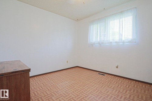 White painted walls with patterned flooring, featuring a window with sheer curtains - 5203 45 Street, Beaumont, AB - Indoor Photo Showing Other Room