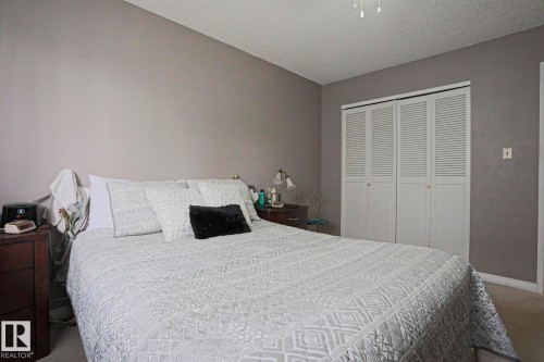 Bedroom featuring neutral painted walls, textured ceiling, and louvered bifold closet doors - 5203 45 Street, Beaumont, AB - Indoor Photo Showing Bedroom