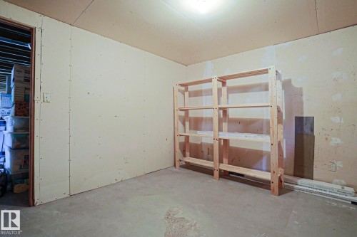 Unfinished room featuring concrete flooring, unpainted wallboard, and exposed ceiling joists - 5203 45 Street, Beaumont, AB - Indoor