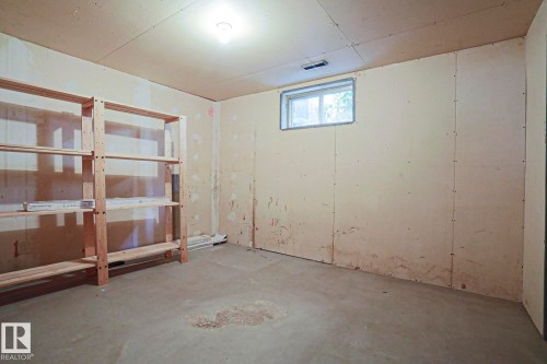 Unfinished basement space featuring exposed wall panels, a concrete floor, and a single window - 5203 45 Street, Beaumont, AB - Indoor Photo Showing Other Room