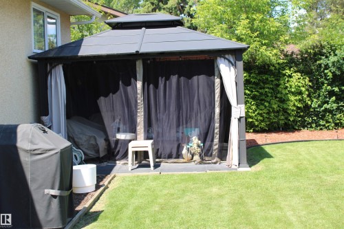 Outdoor gazebo structure featuring a tiered roof, privacy curtains, and insect netting - 5203 45 Street, Beaumont, AB - Outdoor