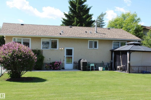Spacious rear yard featuring an expansive lawn, concrete patio, and a covered gazebo - 5203 45 Street, Beaumont, AB - Outdoor