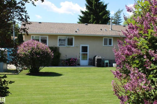 Expansive rear yard featuring a manicured lawn and mature flowering shrubs - 5203 45 Street, Beaumont, AB - Outdoor
