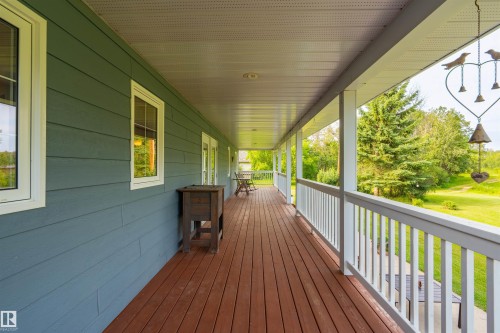 Expansive covered porch featuring wood-finish decking and white railings - 59125 Range Road 102, Rural St. Paul County, AB - Outdoor With Deck Patio Veranda With Exterior