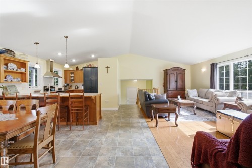 Bright open-concept living space featuring a kitchen with wood cabinetry, a peninsula with bar seating, and stainless steel range hood - 59125 Range Road 102, Rural St. Paul County, AB - Indoor