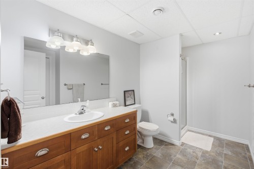 Bathroom featuring a wood-finish vanity with an integrated sink, a large wall mirror, and a four-light fixture - 59125 Range Road 102, Rural St. Paul County, AB - Indoor Photo Showing Bathroom