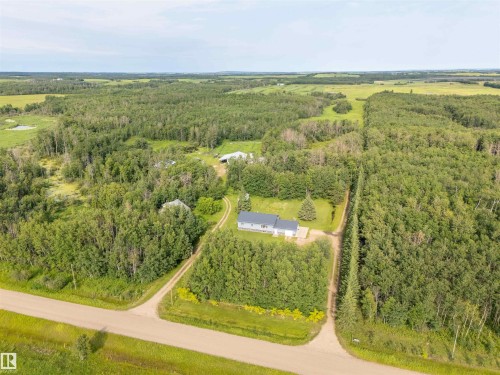 Property surrounded by dense mature trees, featuring a light-colored exterior and a dark roof - 59125 Range Road 102, Rural St. Paul County, AB - Outdoor With View