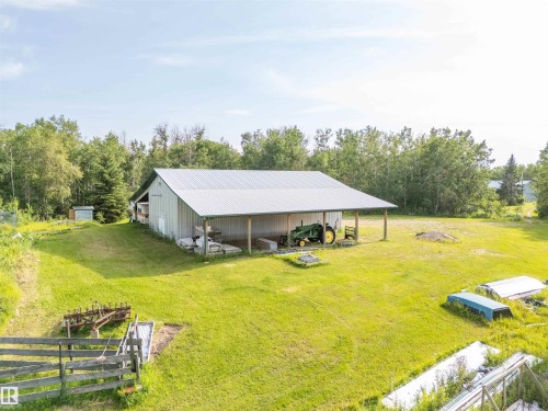 Spacious metal-sided outbuilding with a corrugated metal roof and an open-sided covered area - 59125 Range Road 102, Rural St. Paul County, AB - Outdoor With Deck Patio Veranda