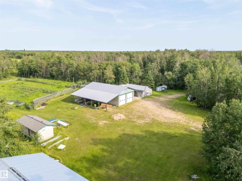 Expansive property featuring multiple outbuildings, including a large structure with dual garage doors and an extended covered area, alongside a smaller shed with a gabled roof - 59125 Range Road 102, Rural St. Paul County, AB - Outdoor With View