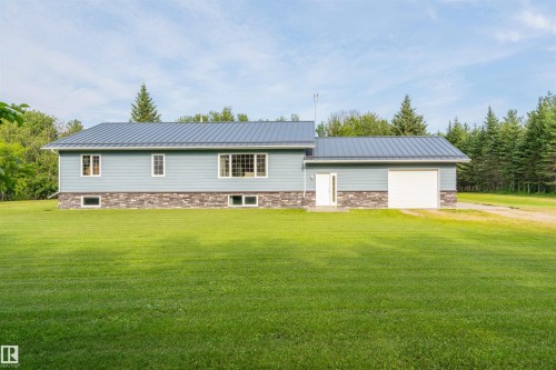 Contemporary residence featuring light blue siding, a metal roof, a stone accent facade, an integrated garage with a white door, and multiple windows - 59125 Range Road 102, Rural St. Paul County, AB - Outdoor