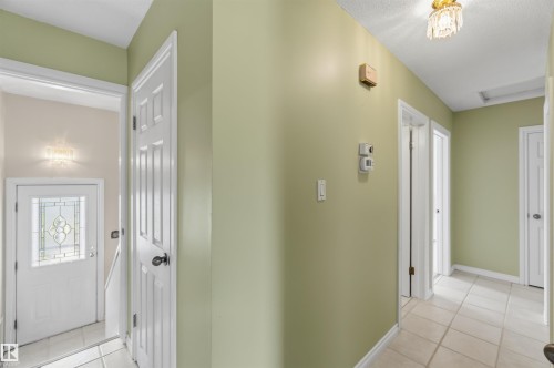 Bright foyer and hallway featuring soft sage-green walls, white six-panel doors, ceramic tile flooring, and recessed ceiling lighting - 8031 135A Avenue Nw, Edmonton, AB - Indoor Photo Showing Other Room
