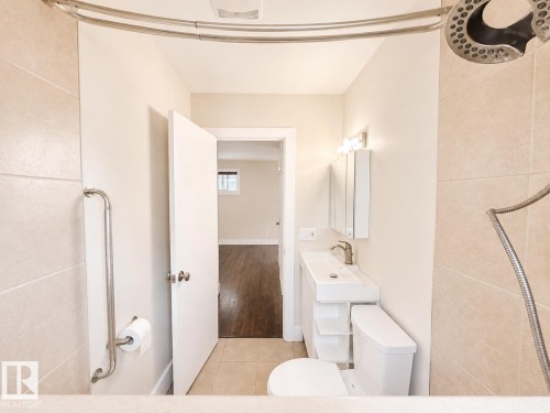 Bathroom featuring a floating vanity with an integrated sink, polished chrome faucet, and a wall-mounted medicine cabinet - 11934 64 Street Nw, Edmonton, AB - Indoor Photo Showing Bathroom