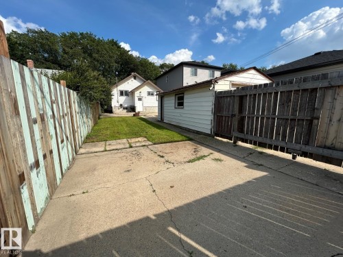 Spacious backyard with mature landscaping, wooden privacy fencing, and multiple outbuildings - 11934 64 Street Nw, Edmonton, AB - Outdoor With Exterior