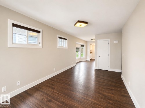 Wood-finish flooring, neutral wall paint, white trim, recessed lighting, and multiple windows - 11934 64 Street Nw, Edmonton, AB - Indoor Photo Showing Other Room