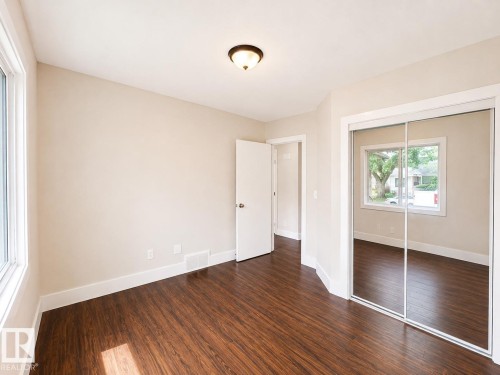 Wood-finish flooring, white trim details, flush-mount ceiling light fixture, and mirrored closet doors - 11934 64 Street Nw, Edmonton, AB - Indoor Photo Showing Other Room