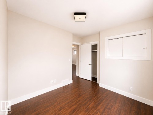 Wood-finish flooring, white trim, recessed wall feature, closet with bifold doors, and a ceiling-mounted light fixture - 11934 64 Street Nw, Edmonton, AB - Indoor Photo Showing Other Room