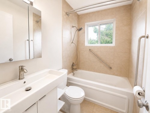 Bathroom featuring a modern vanity with integrated sink, brushed nickel faucet, tiled shower/tub combination, and built-in grab bars - 11934 64 Street Nw, Edmonton, AB - Indoor Photo Showing Bathroom
