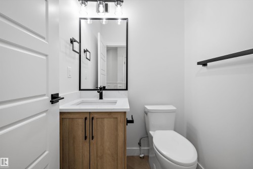 Wood-finish vanity with a white countertop and integrated sink, complemented by a black-framed mirror - 971 Elderberry Landing Nw, Edmonton, AB - Indoor Photo Showing Bathroom