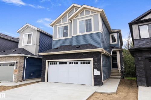 Two-story residence featuring blue siding, white trim accents, a single-car garage, and a stacked stone facade - 971 Elderberry Landing Nw, Edmonton, AB - Outdoor