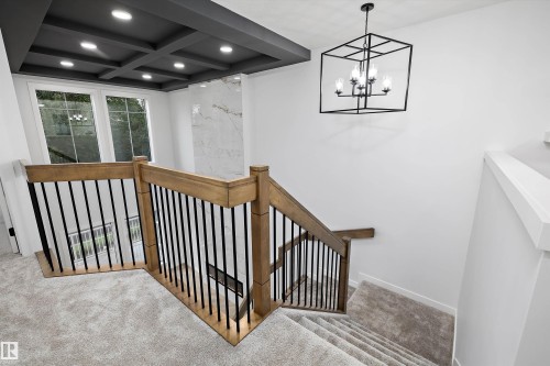 Carpeted upper landing with wood-finish handrails and black metal balusters - 971 Elderberry Landing Nw, Edmonton, AB - Indoor Photo Showing Other Room