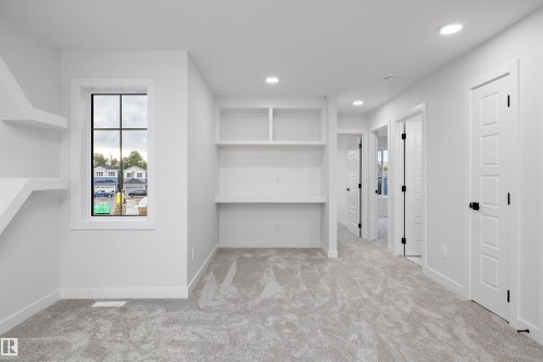Built-in desk with shelving, recessed lighting, double-pane window, wall-mounted shelving, and paneled interior doors with matte black hardware - 971 Elderberry Landing Nw, Edmonton, AB - Indoor Photo Showing Other Room