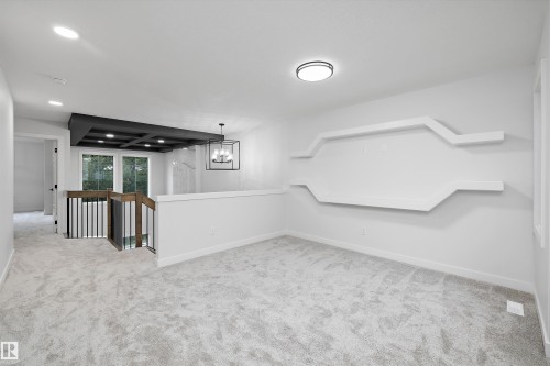 White wall with integrated decorative shelving, flush mount ceiling fixture, and light gray carpeted flooring - 971 Elderberry Landing Nw, Edmonton, AB - Indoor Photo Showing Other Room