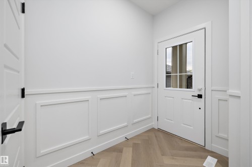 Herringbone wood-finish flooring complements the wainscoting - 971 Elderberry Landing Nw, Edmonton, AB - Indoor Photo Showing Other Room