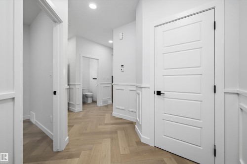 Herringbone wood-finish flooring, recessed lighting, and wainscoting detailing enhance the hallway - 971 Elderberry Landing Nw, Edmonton, AB - Indoor Photo Showing Other Room