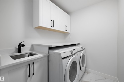 White shaker-style cabinetry with matte black hardware, stainless steel utility sink with a matte black faucet, and light-toned countertop - 971 Elderberry Landing Nw, Edmonton, AB - Indoor Photo Showing Laundry Room