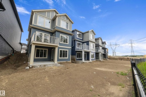 Three-story structure with blue siding, white trim, and a second-level balcony with white railings - 971 Elderberry Landing Nw, Edmonton, AB - Outdoor