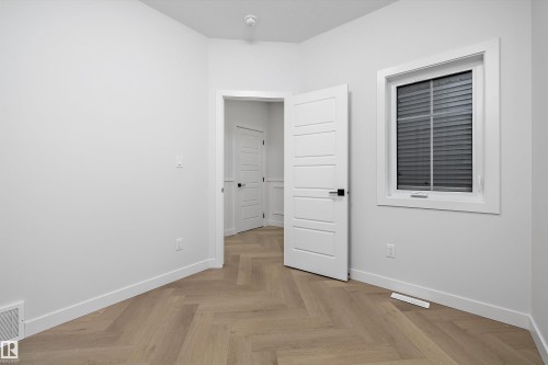 Herringbone wood-finish flooring, white paneled interior doors, white trim, and a window with blinds - 971 Elderberry Landing Nw, Edmonton, AB - Indoor Photo Showing Other Room