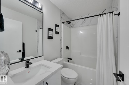 Modern bathroom featuring a white vanity with integrated sink, black-finish faucet, and a black-framed mirror - 265 Edgemont Green Nw, Edmonton, AB - Indoor Photo Showing Bathroom