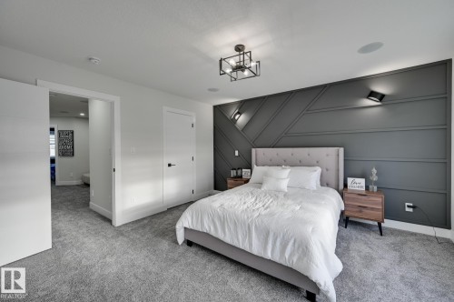 Geometric accent wall with integrated wall sconces, ceiling-mounted light fixture, recessed ceiling speakers, and light gray carpeting - 265 Edgemont Green Nw, Edmonton, AB - Indoor Photo Showing Bedroom
